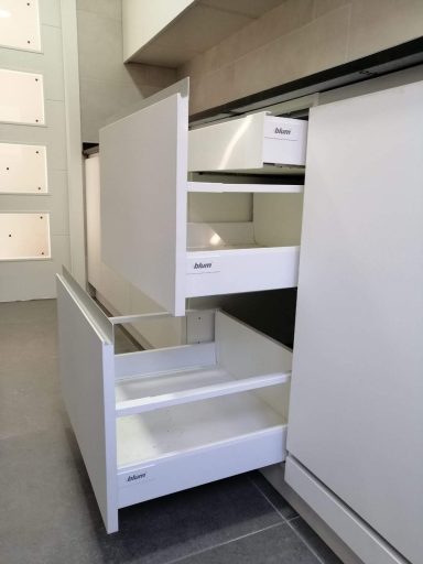 Mueble de cocina con cajones blancos parcialmente abiertos en un entorno moderno.