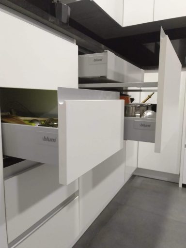 Muebles de cocina modernos con cajones y puertas abiertas, variedad de utensilios visibles.