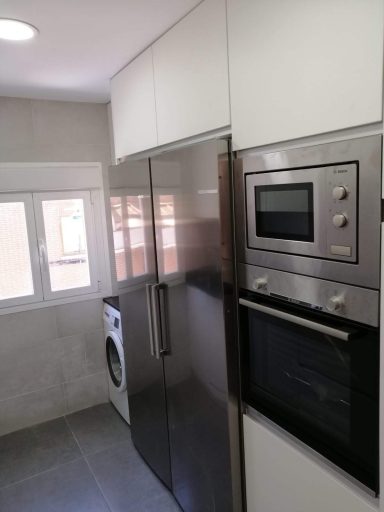 Cocina moderna con refrigerador, horno, microondas y lavadora integrada.