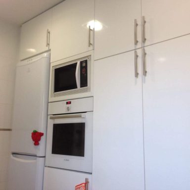 Cocina moderna con muebles blancos y electrodomésticos en color inox.