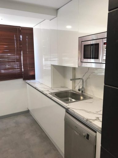 Cocina moderna con encimera de mármol, fregadero y electrodomésticos stainless steel.