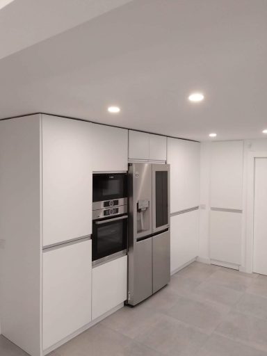 Cocina moderna con electrodomésticos de acero inoxidable y paredes blancas.