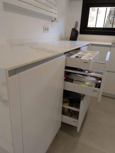 Mueble de cocina blanco con cajones abiertos y superficie de trabajo.