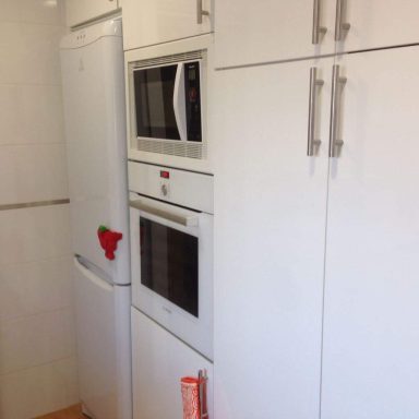 Cocina con muebles blancos y electrodomésticos integrados.