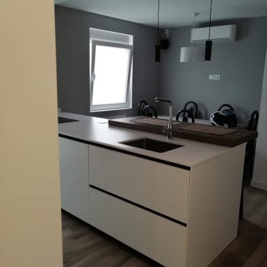 Cocina moderna con isla central y accesorios de acero en un ambiente minimalista.