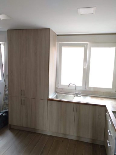 Cocina moderna con muebles de madera clara y ventana iluminada.
