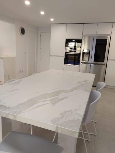 Cocina moderna con una isla central de mármol y electrodomésticos de acero inoxidable.