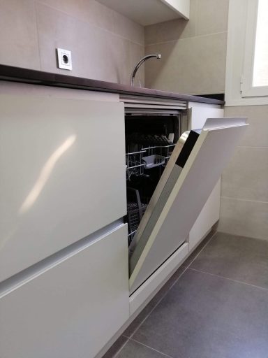 Lavavajillas integrado abierto en una cocina moderna con paredes claras.