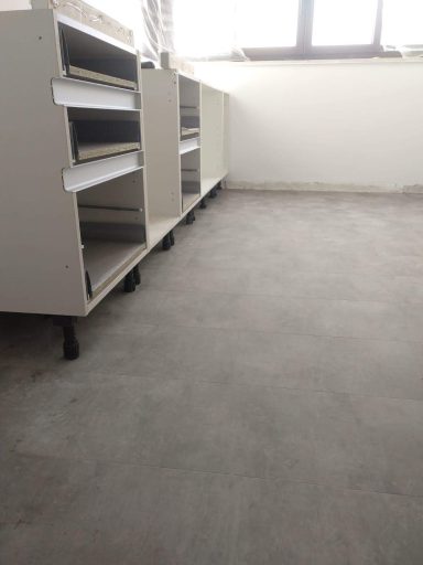 Mueble con estantes blancos y suelo de cemento en un espacio luminoso.