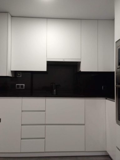 Cocina moderna con muebles blancos y una encimera negra.