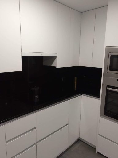 Cocina moderna con muebles blancos y encimera negra.
