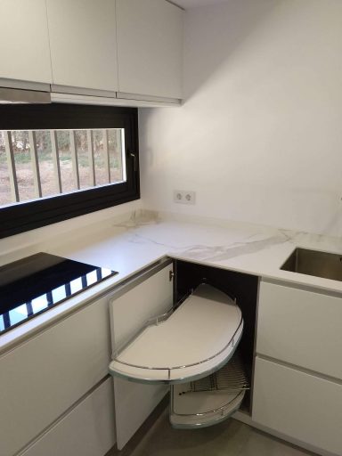 Cocina moderna con encimera blanca, fregadero y una zona de trabajo retráctil.