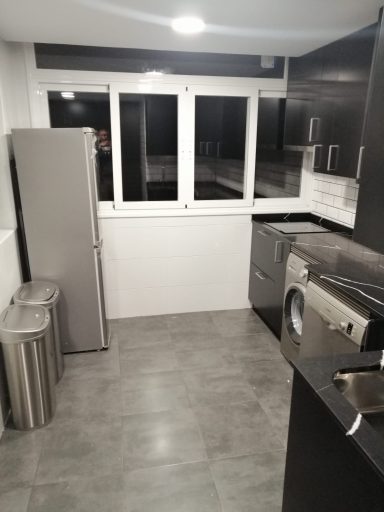 Cocina moderna con electrodomésticos de acero inoxidable y grandes ventanales.